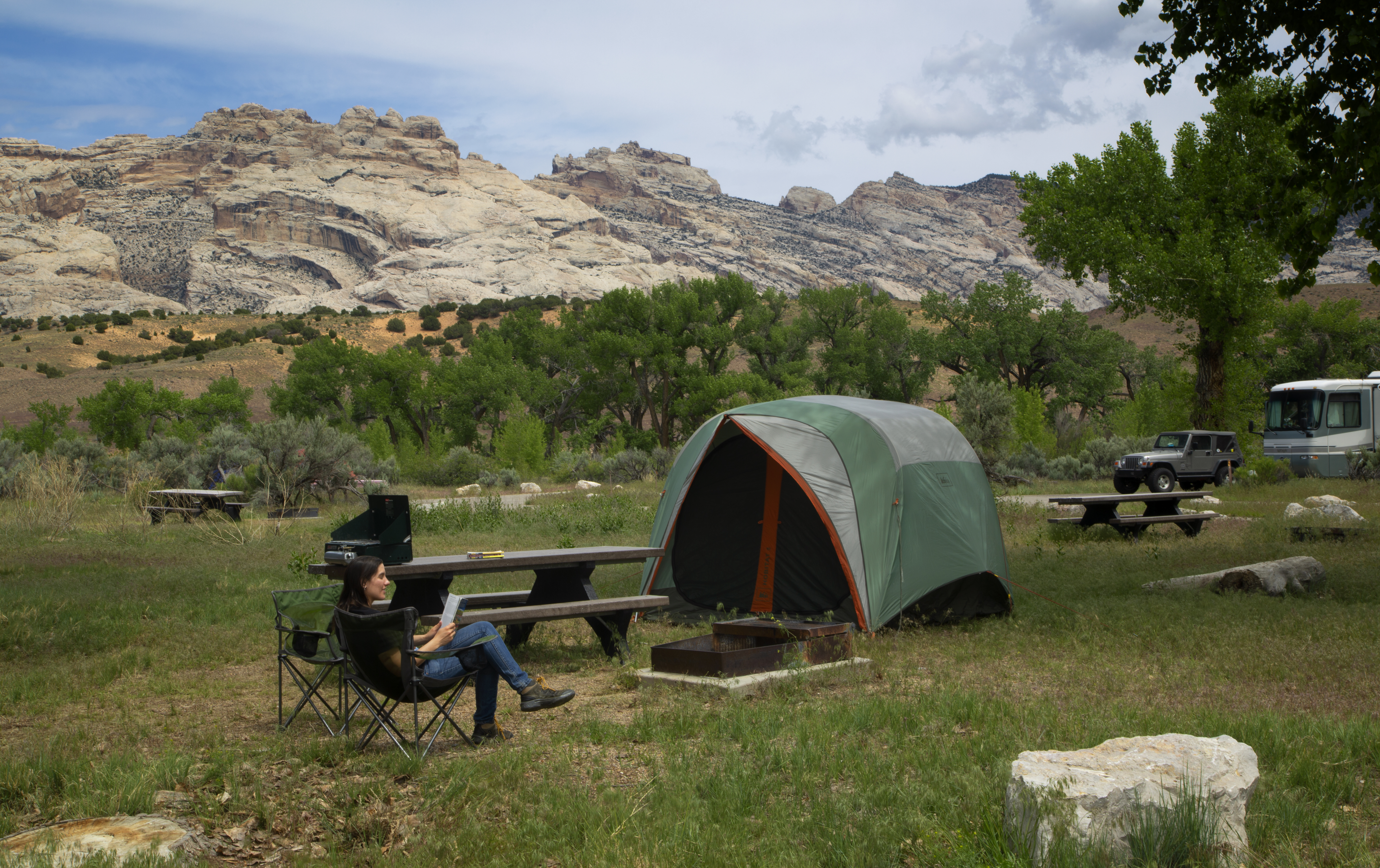 Camper at the Green River Campground Woman sitting in a chair in front of a tent with a rock mountain in the background