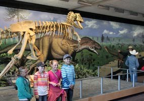 Several young dinosaur enthusiasts pose in front of the Allosaurus reconstruction at the Quarry Exhibit Hall.
