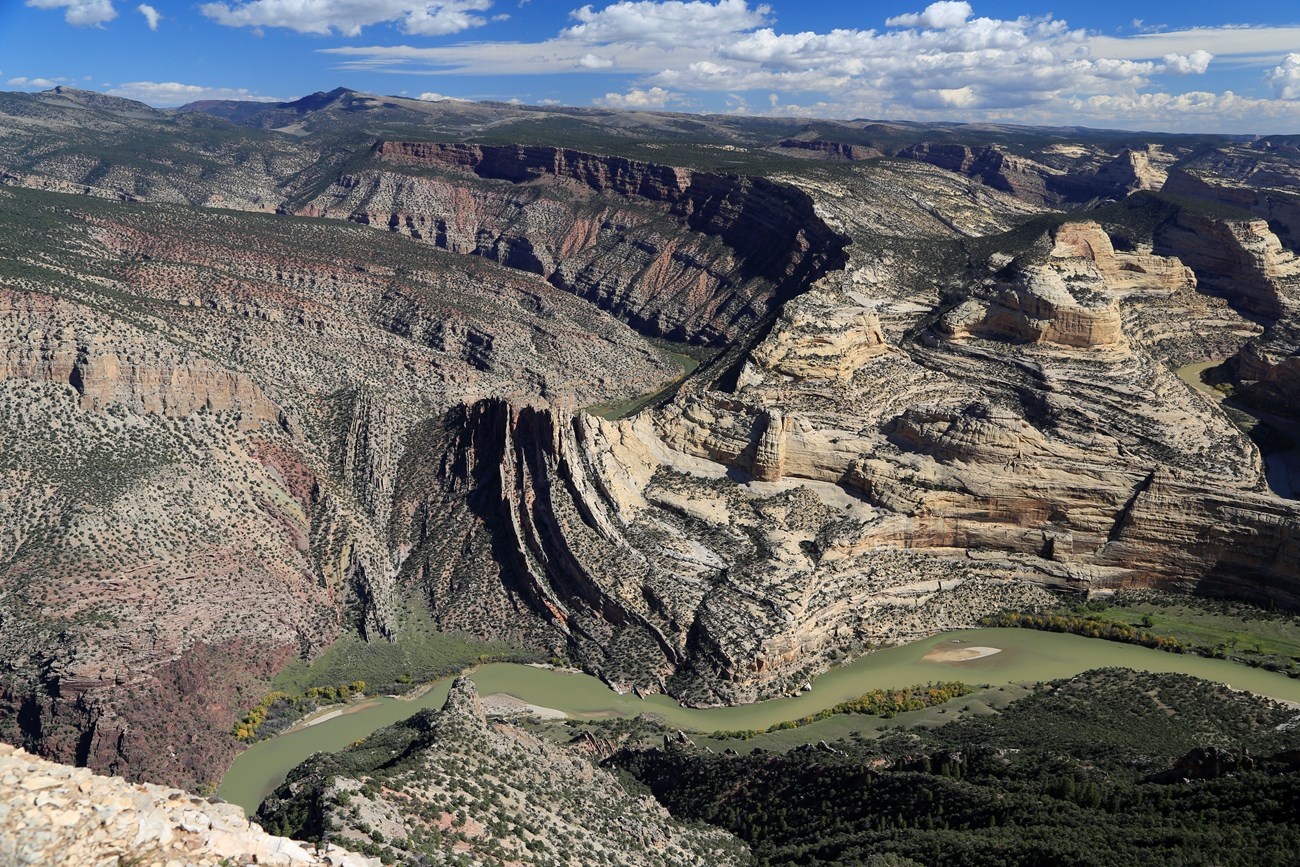 View of tan and multi-colored cliffs rising above a river