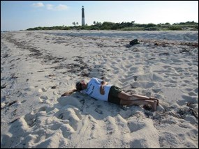 Biologist sprawled across the tracks left by a nesting leatherback sea turtle