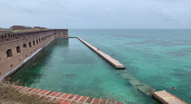 Breach in moat wall of Fort Jefferson A view of the broken section of the moat wall in front of the brick fort with a view out to shallow green water