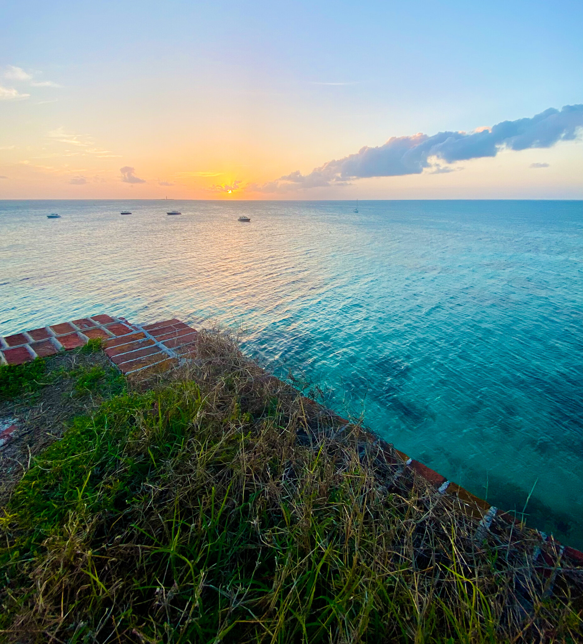 Fort Jefferson Sunrise The sun turns the sky pink and orange as it rises above the blue ocean.