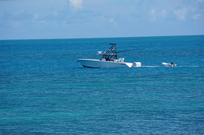 A large boat towing a dinghy, moving across water