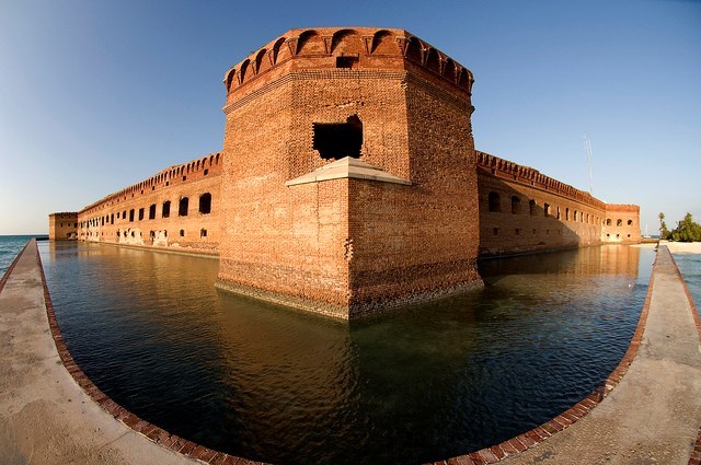a moat surrounding a large stone fortress taken through a fisheye lense