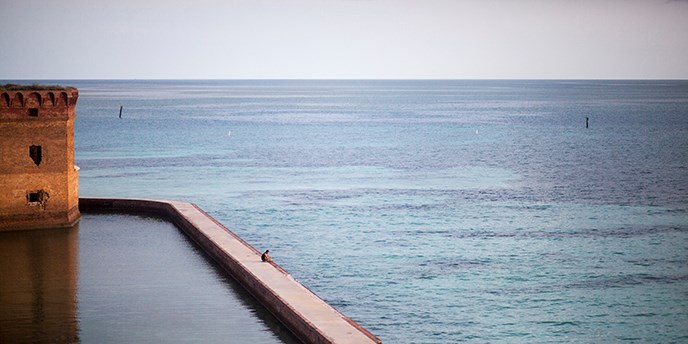 People walk the moat wall at Garden Key. People walk the moat wall at Garden Key.