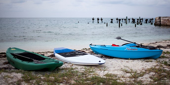 Kayak and paddleboard are parked on the beach. Kayak and paddleboard are parked on the beach.