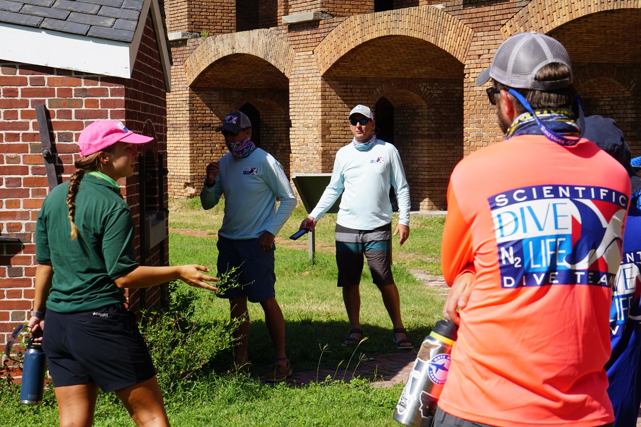 A woman leading a tour group in front of a brick structure