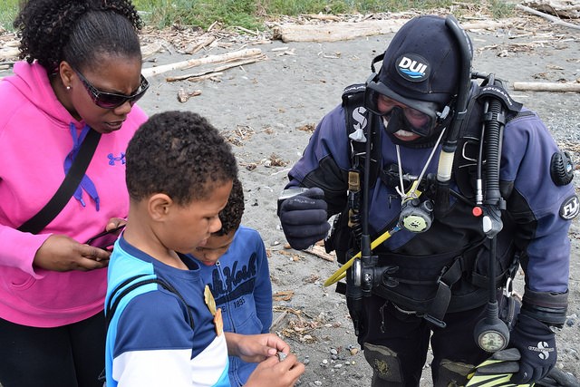 Two boys with adult talking to a skindiver.