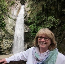 Smiling woman in front of waterfall.