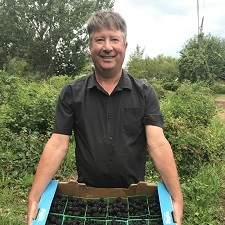 Man holding box with blackberries.