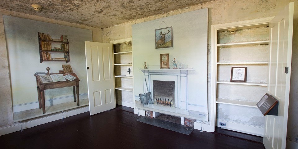 Color photo of a small room with life-size illustrations of a writing desk, bookshelf, and chimney on the walls.