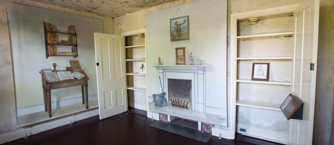 Color photo of the parlor in the Poe House, a small room with illustrations of furniture on the walls, but no real furniture. Color photo of the parlor in the Poe House, a small room with illustrations of furniture on the walls, but no real furniture.