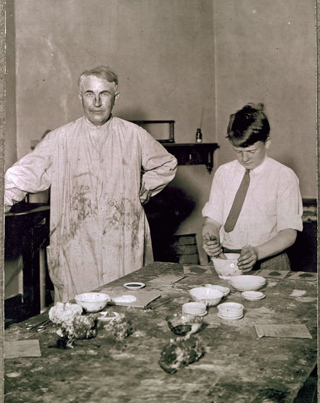 Thomas Edison and his school age son Charles at home working on an experiment.