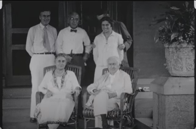 Black and white photo of Thomas and Mina Edison and family sitting under the porch at Glenmont.