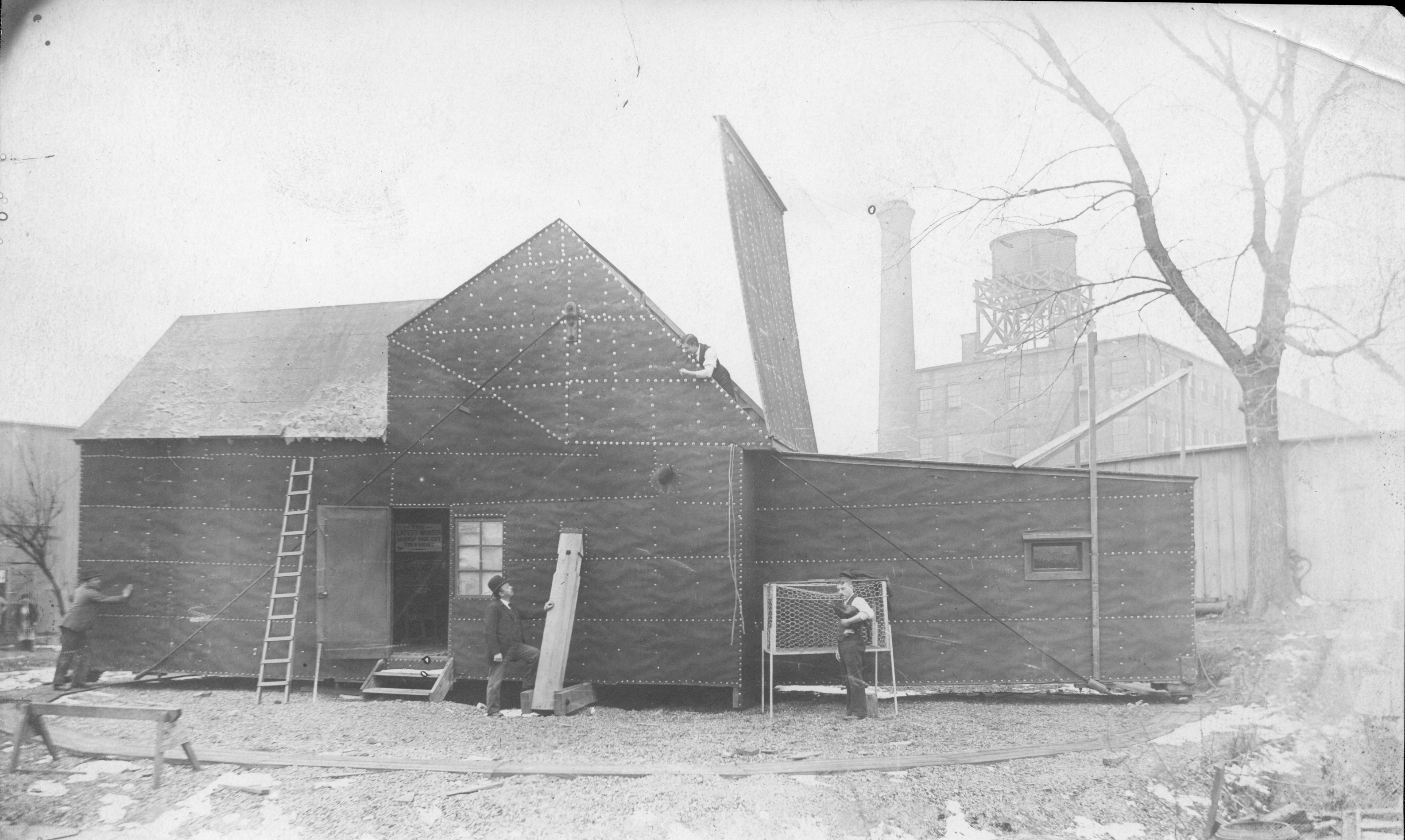 A historic photo of black papered building used as a film studio with workers nearby.