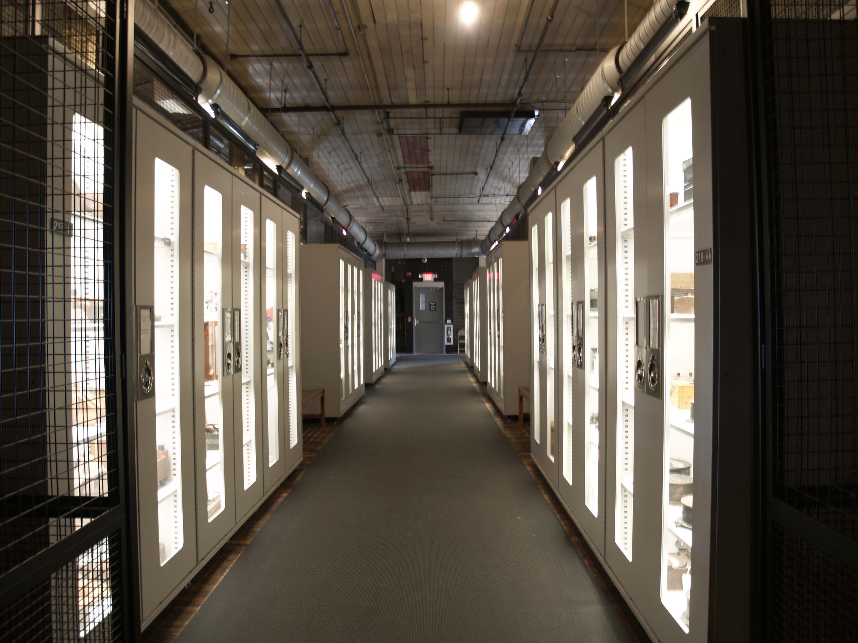 This picture is on the 3rd floor of building 5.  There are white display cases on both sides of the hallway.  These display cases house some of the many artifacts from the site.
