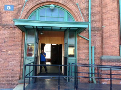 Two open metal doors leading to small wooden foyer which also has open doors at main laboratory.