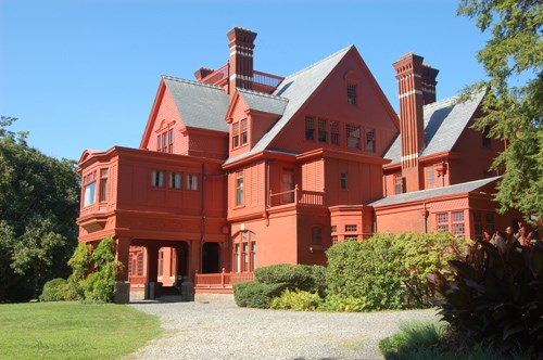 Glenmont Brick red, four story mansion with multiple roofs and chimneys.