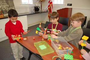 A group of children try their hand at inventing using TinkerToys.