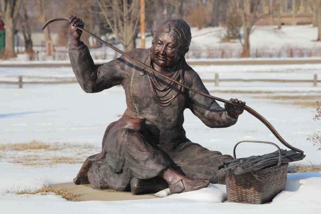 Bronze statue of Emma Big Bear weaving a basket
