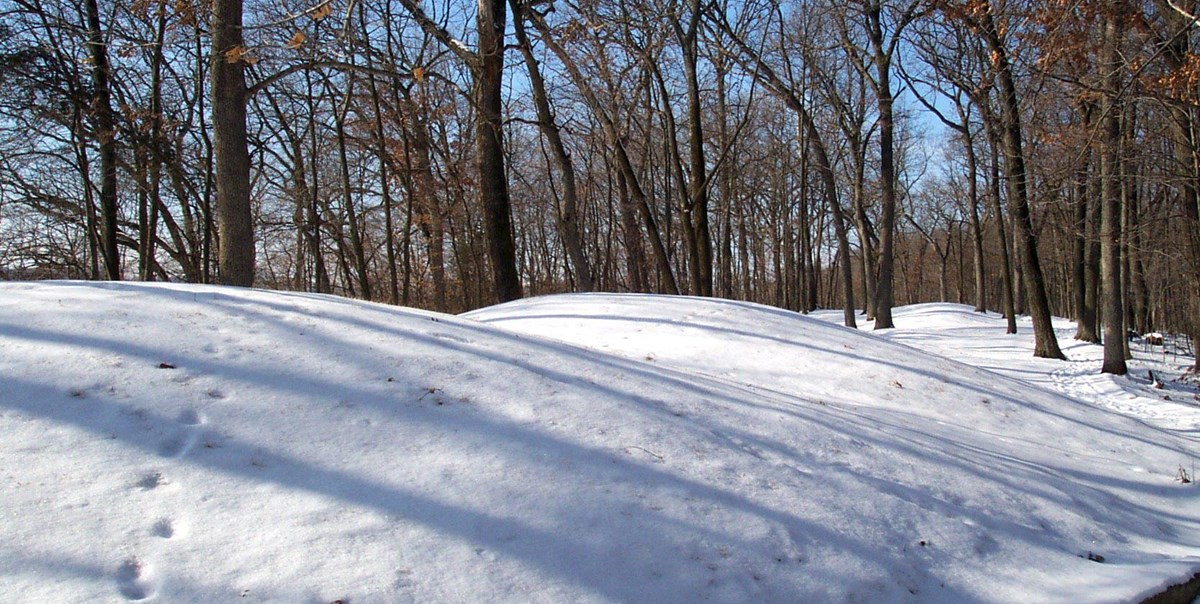 Prehistoric burial mounds covered in snow.