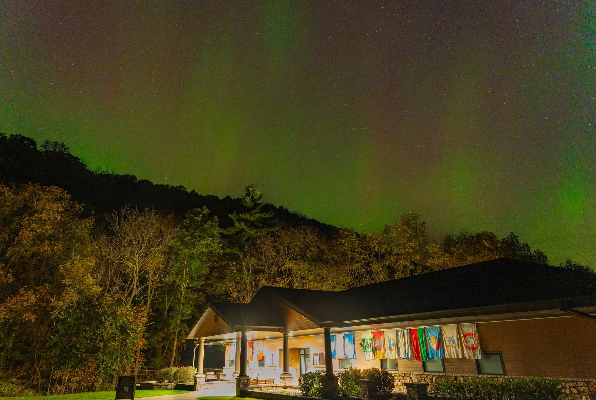Image of the visitor center lit up at night with the aurora borealis in the background sky.