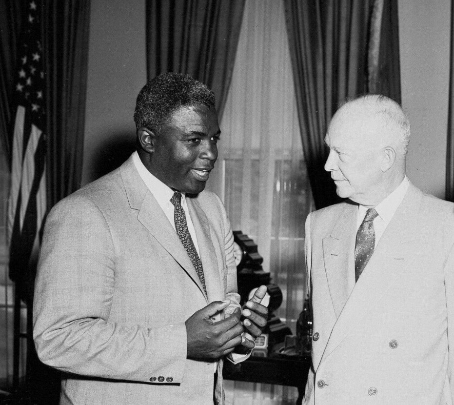 Black and White Photograph of Jackie Robinson, standing left, talking with President Dwight Eisenhower in the Oval Office in the White House