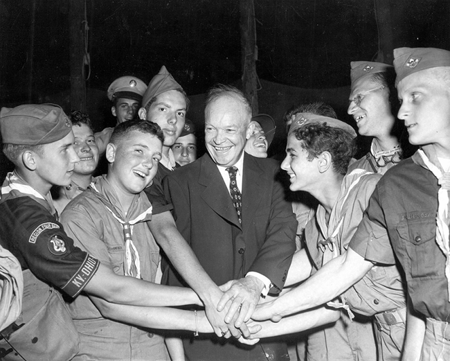 A black and white photograph of a group of boy scouts gathered around Dwight Eisenhower