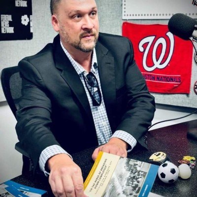 An image of a man in a sport coat and dress shirt seatetd at a table