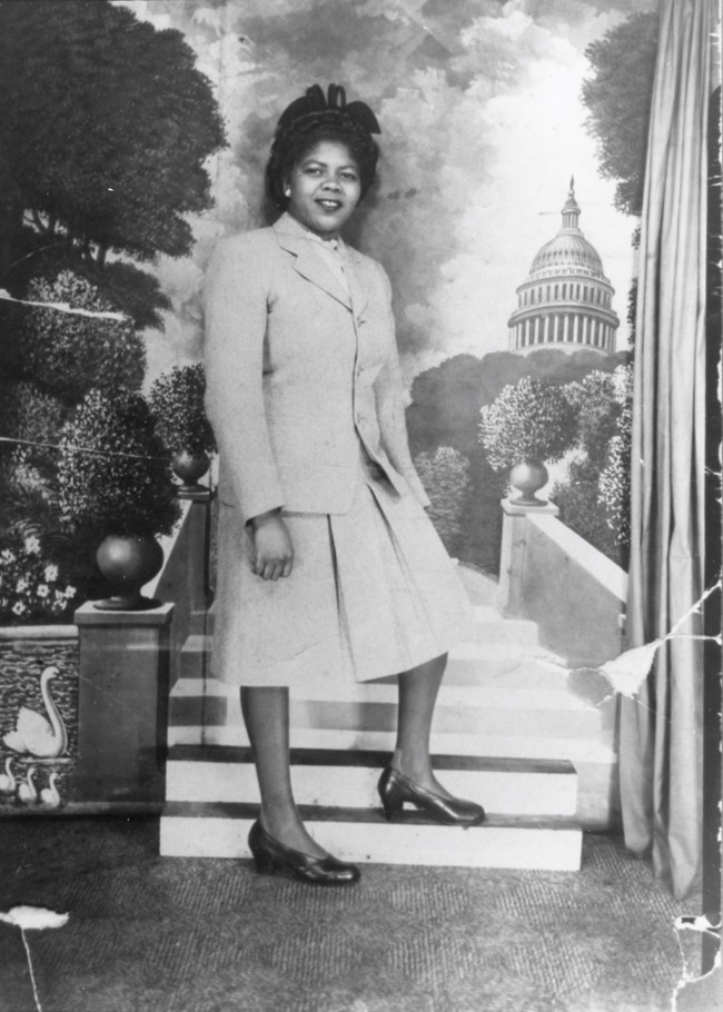 Delores Moaney ca. 1944 Delores Moaney stands for a photograph; she is wearing a dress. In the background is an image of the US Capitol Building