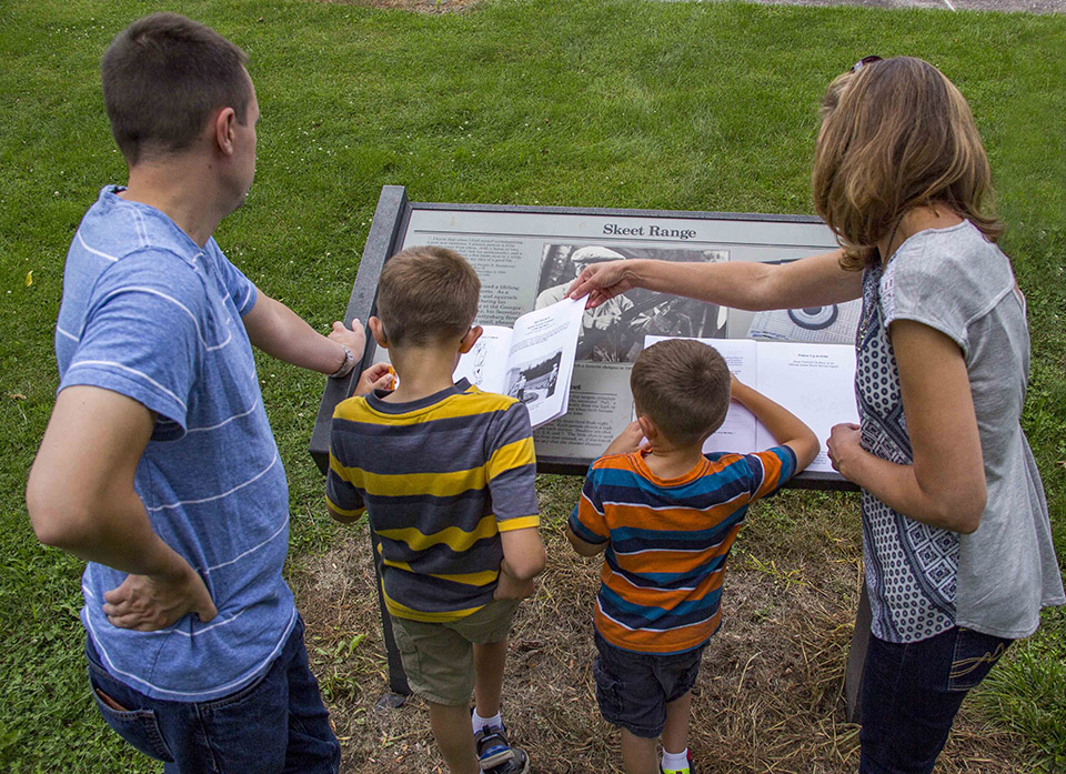 A family of four works on the Eisenhower Junior Ranger book at the skeet range.