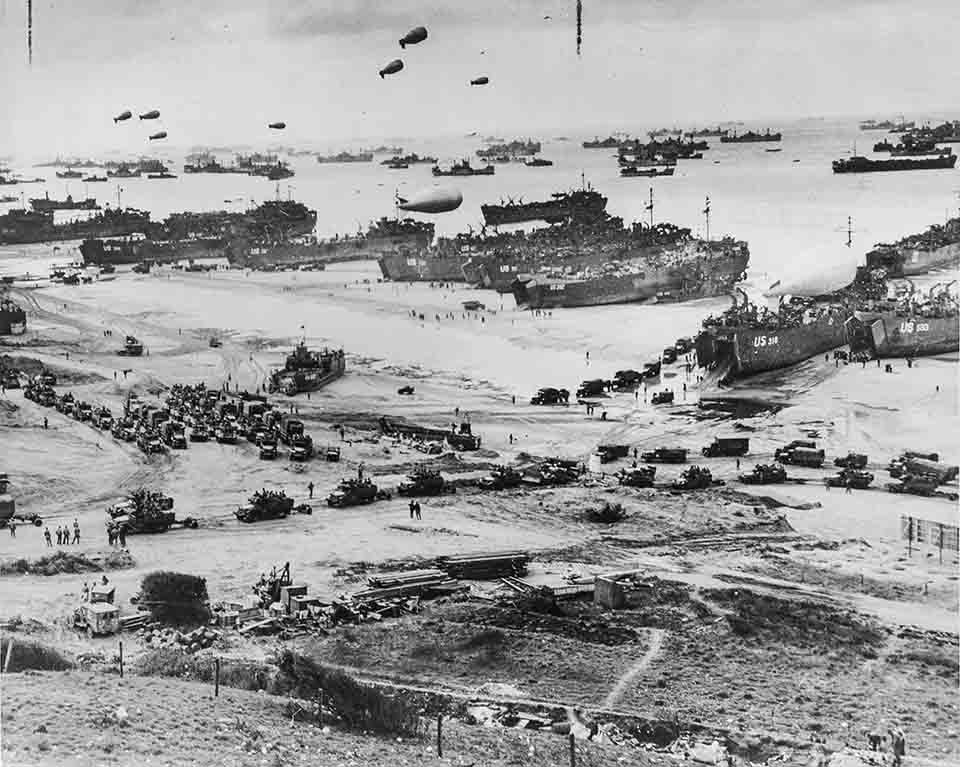 A very busy aerial picture of Normandy Beach, France in 1944 as dozens of Allied transport ships unload their cargoes of tanks, vehicles, and soldiers. A very busy aerial picture of Normandy Beach, France in 1944 as dozens of Allied transport ships unload their cargoes of tanks, vehicles, and soldiers.