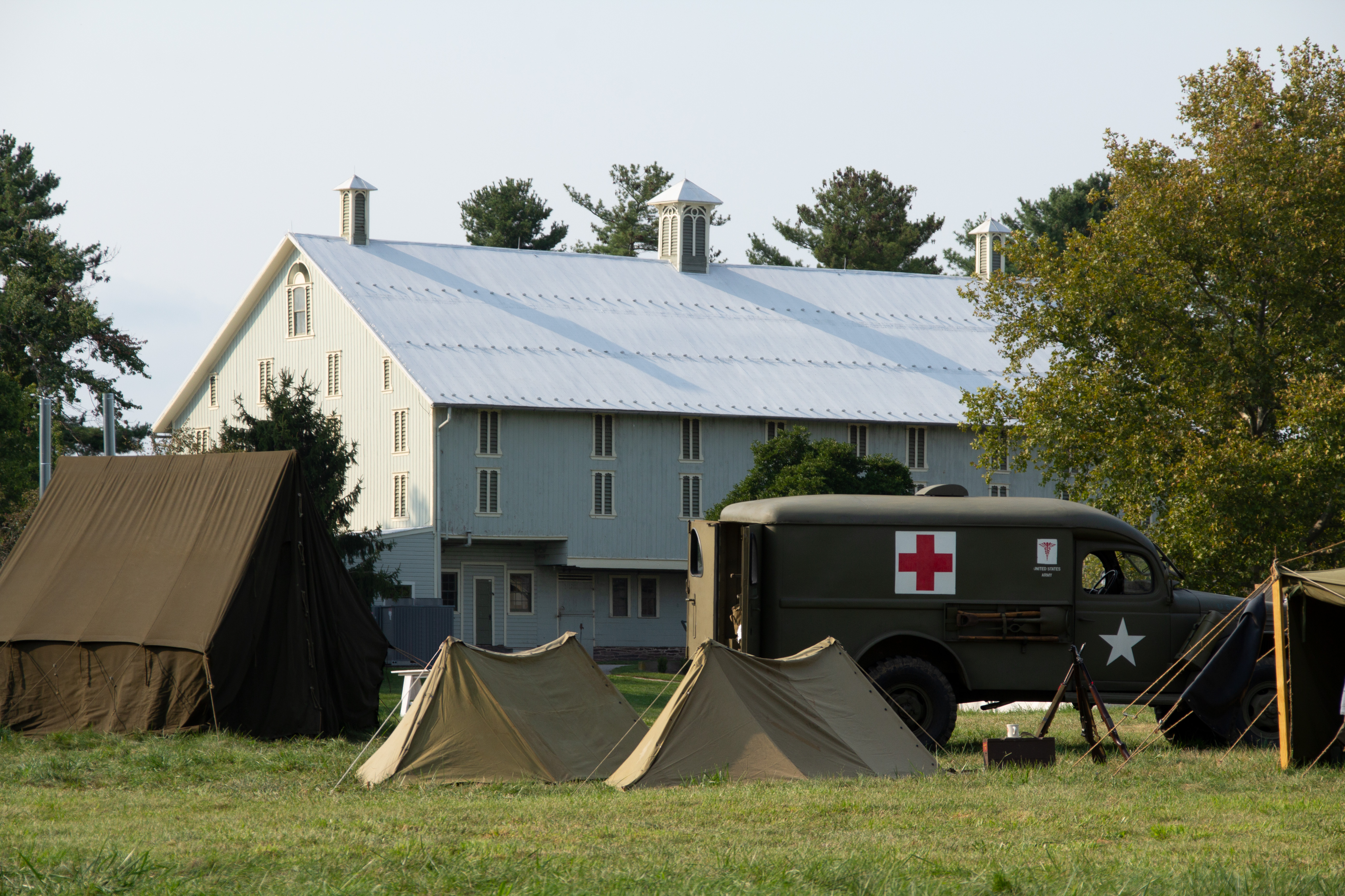 World War II Weekend at Eisenhower National Historic Site. A large white barn stands in the distance with World War II tents and medical truck are in the foreground.