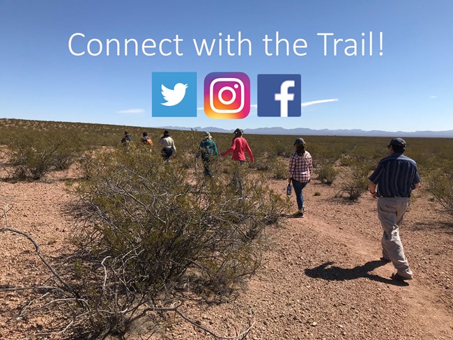 People walk down a trail through a desert setting.
