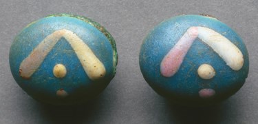 Sleeve links - blue oval with yellow, pink and white symbols - found in individual burial Sleeve links - blue oval with yellow, pink and white symbols - found in individual burial