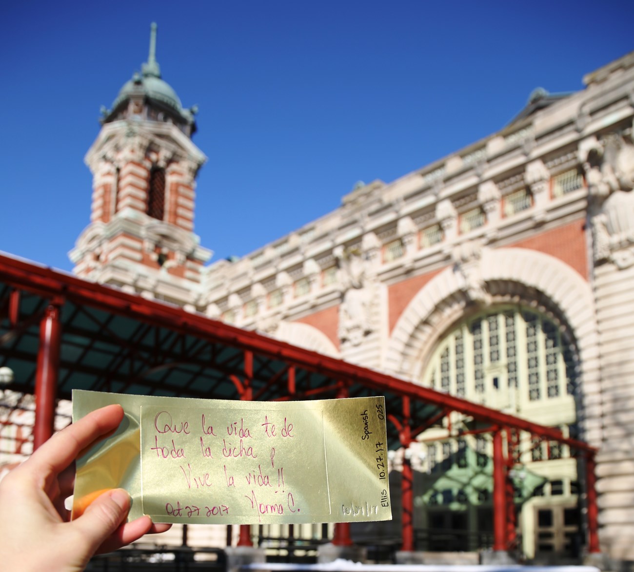Gold brick with message from visitor in front of Ellis Island.