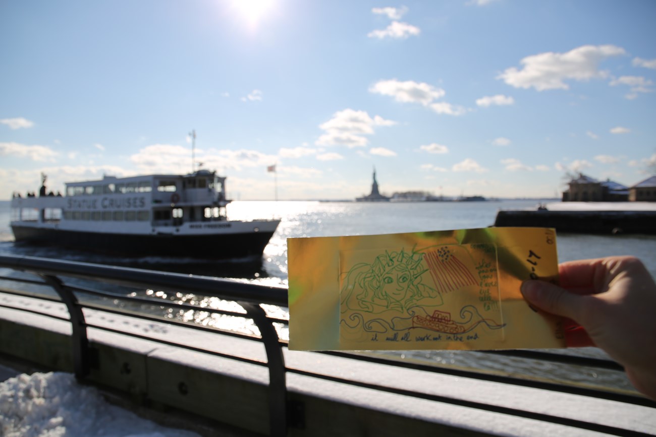 Gold brick with message from visitor with New York Harbor in background.