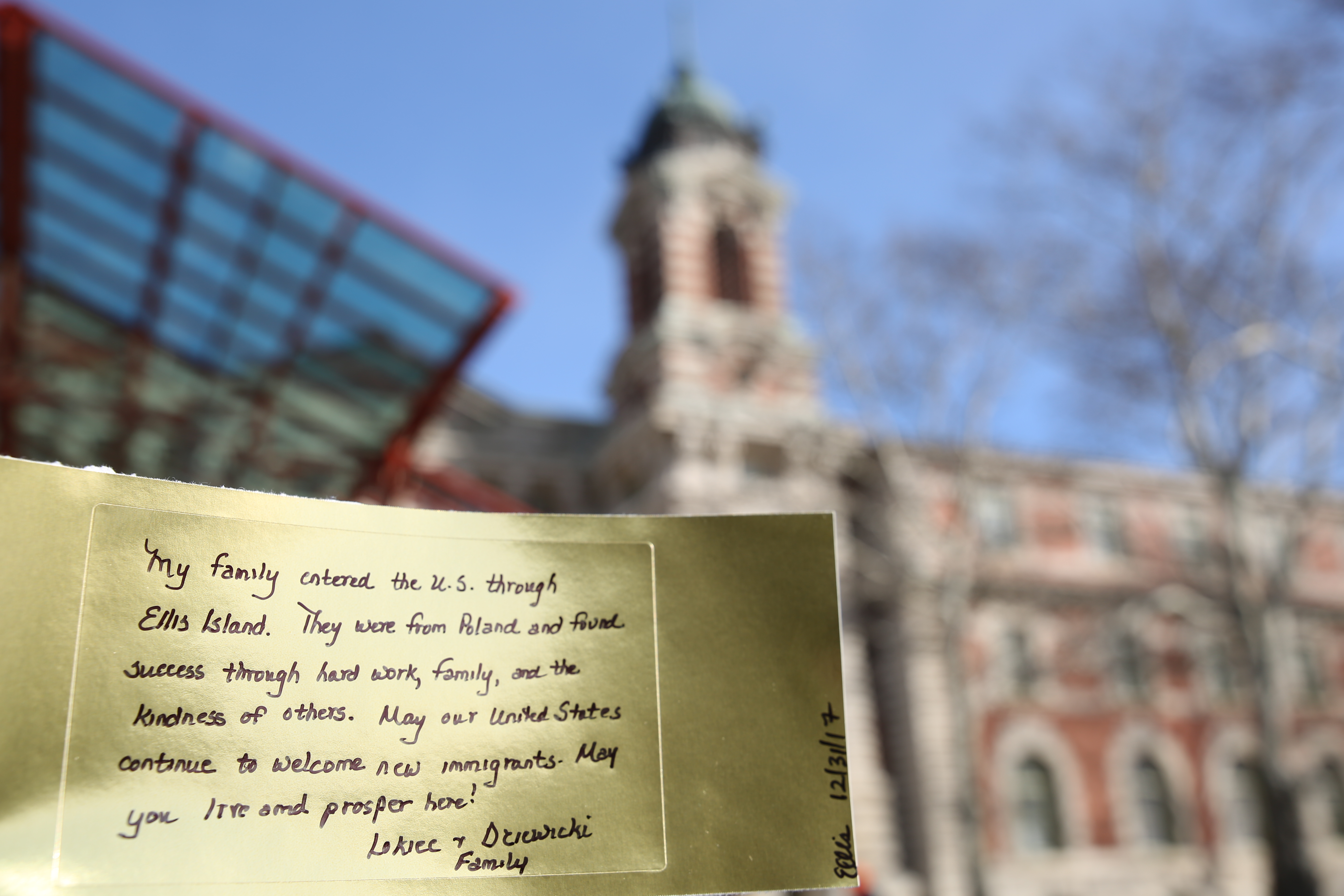 Gold brick with message from visitor in front of Ellis Island.