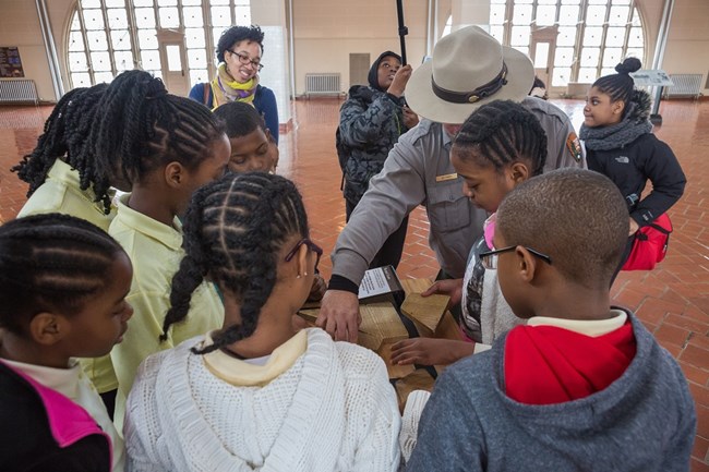 Kids watch a ranger demonstrating a puzzle on Ellis Island