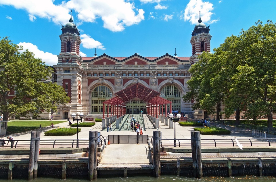Main Building Ellis Island National Museum of Immigration outside of museum building with visitors and entrance canopy