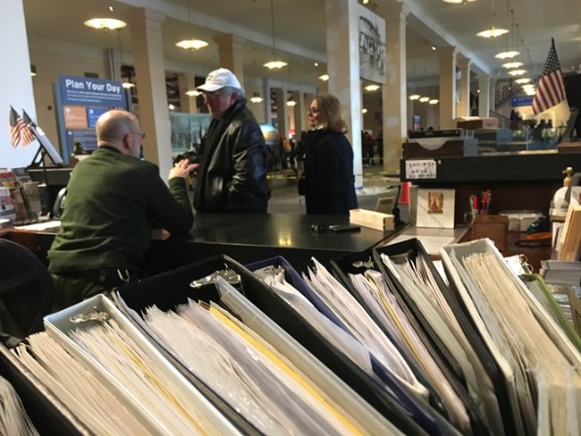 A park ranger answering a man and woman's question at the information desk.