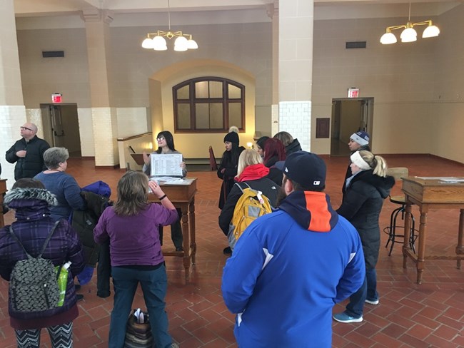 A park ranger using a ship manifest document to teach about immigration to a crowd.