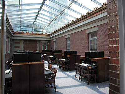 Brick walled room with clear glass peaked roof. Uniform chairs and desks throughout