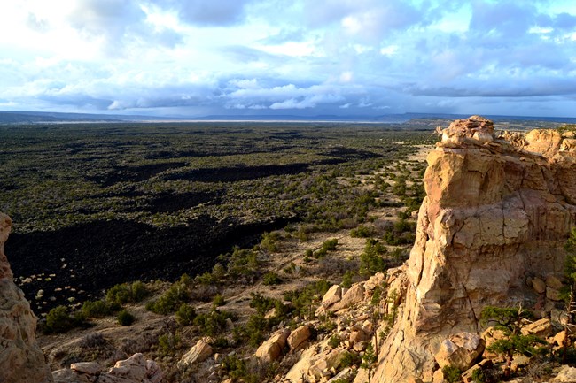 Craggy sandstone cliffs frame the rugged lava flows below them.