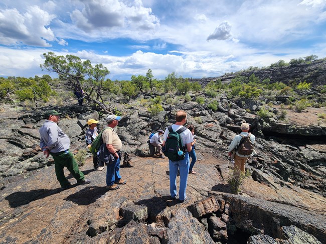 A group of hikers on a very young lava flow looking at lava features.
