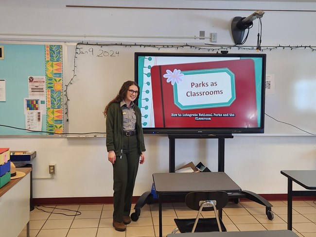 female ranger in a classroom with a presentation that says "Parks as Classrooms"