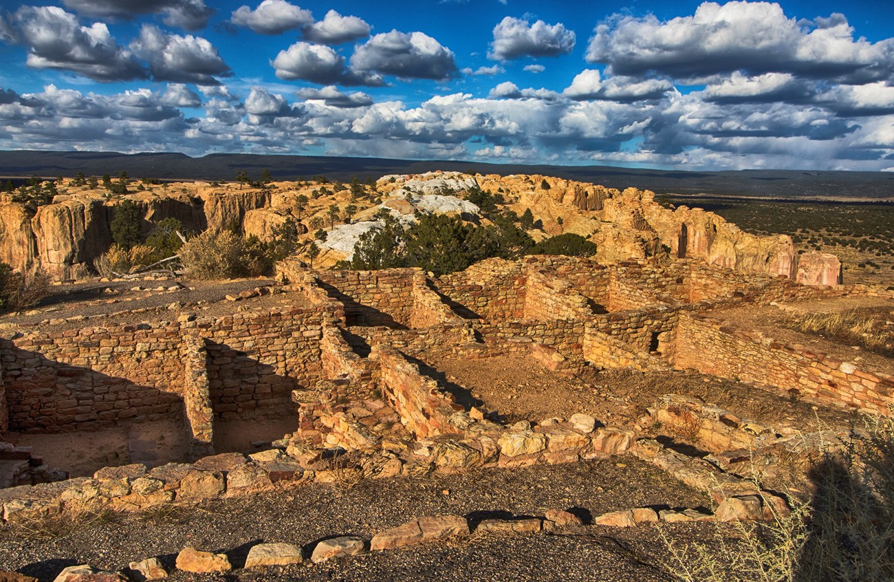 The excavated rooms of a pueblo overlooking a valley