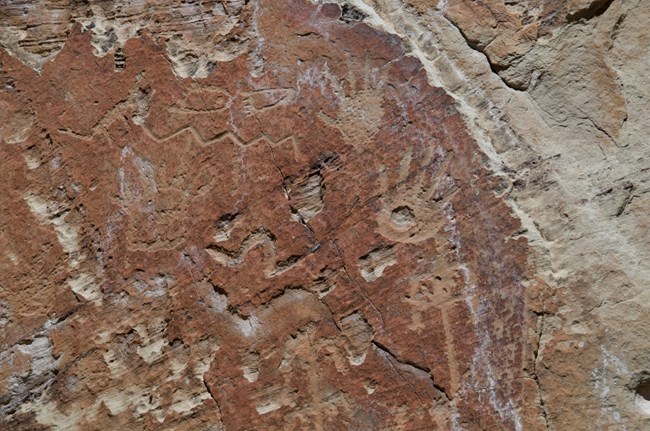 Reddish sandstone with petroglyphs carved into the surface.
