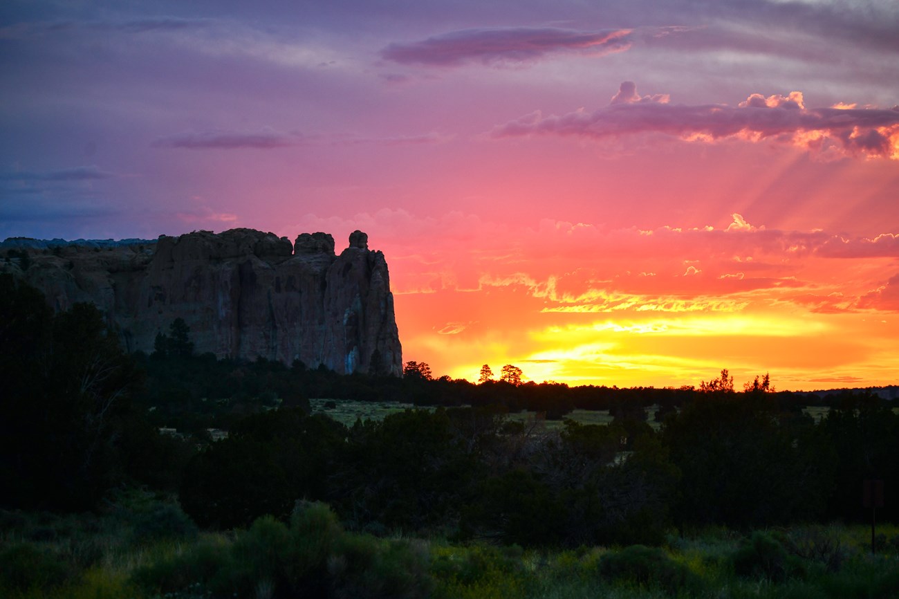 A cliff silhouetted against a yellow and pink sunset
