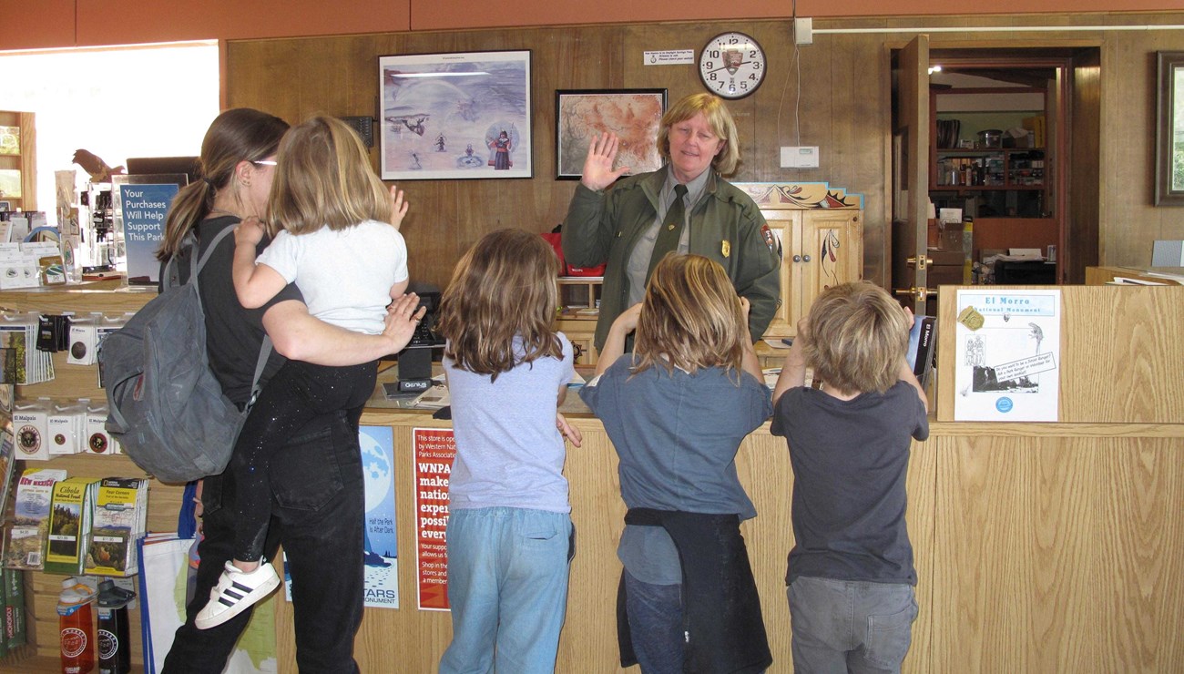 Three Jr. Rangers take their pledge froam a ranger while mom and little sister watch.